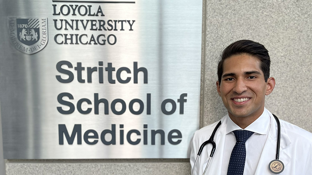 Medical student Nathan Dhablania standing next to Stritch School of Medicine sign